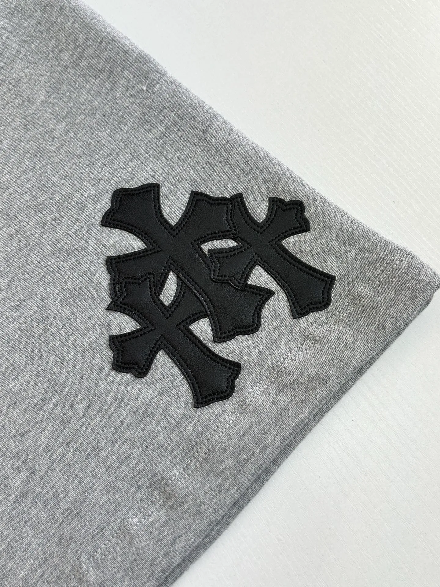 P346 Chrome Hearts*/Chrome Hearts 26SS early spring new patch embroidered shorts The fabric is made of a blended ratio of 80% cotton and 20% polyester. It is woven with a siro spinning process of 32-count base yarn and 10-count veil to form a high-weight terry cloth base of 380g/㎡. The cotton-polyester blended material combines the skin-friendly breathability of cotton and the anti-wrinkle shape retention of polyester. The high-weight fabric gives the trousers excellent stiffness and drape. The core technology is patch embroidery, which is completed with the help of TAJIMA computer embroidery machine. The black special-shaped patch is precisely sewn to the trouser fabric through lock stitches. The embroidery stitch density is even and the edges are neatly hemmed, forming a three-dimensional relief-like visual effect. Size: S/M/L/XL